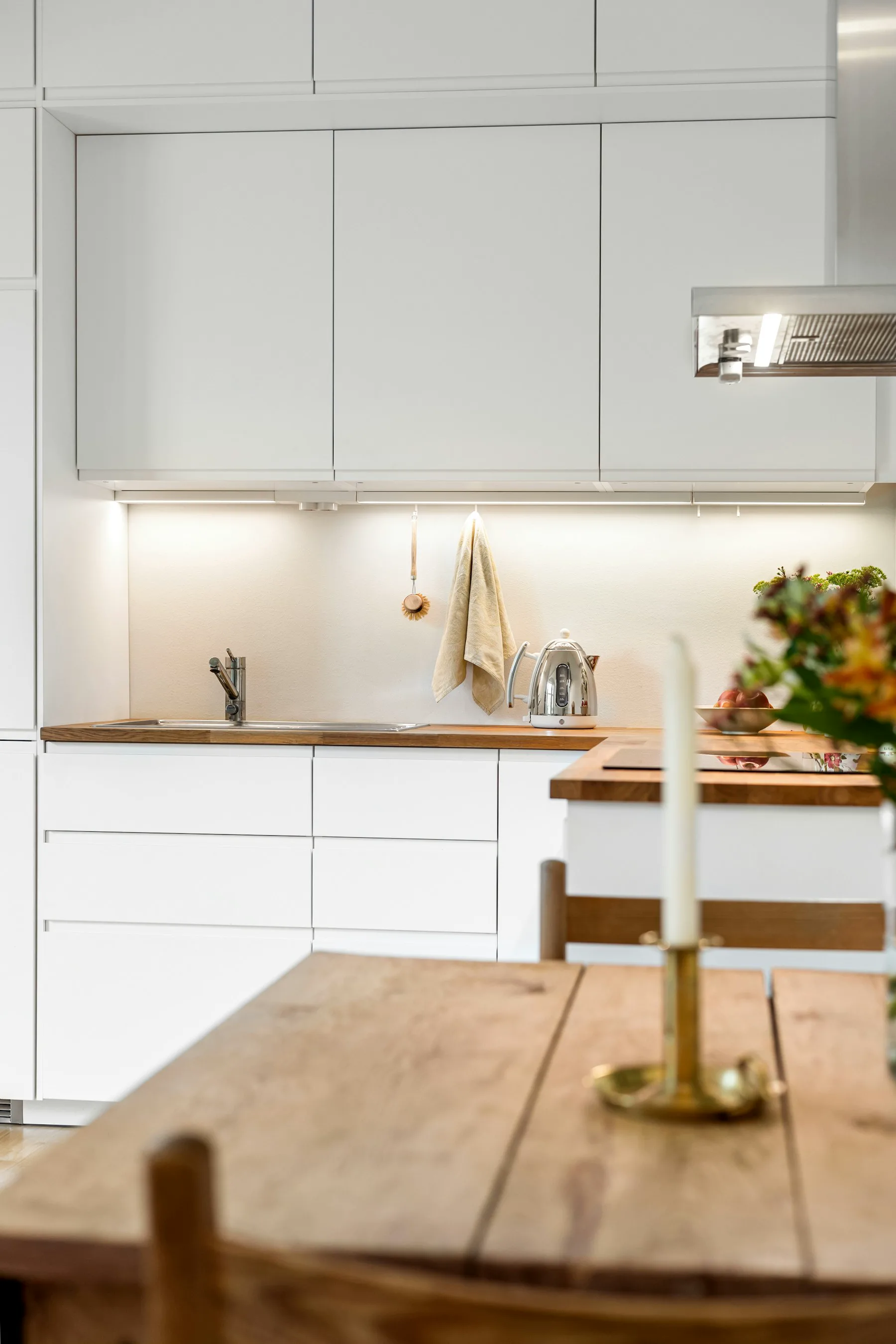 White kitchen cabinets with oak worktops and an island