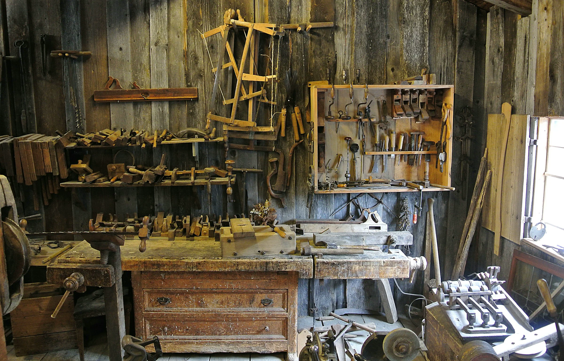 A broad timber workbench with tools arranged across its surface