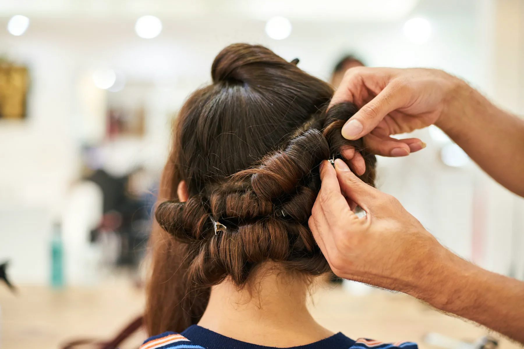 A stylist arranging a client's hair into a loose bun