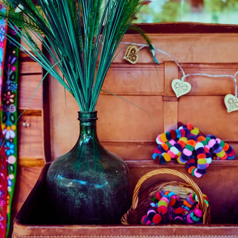 A dark blue glass vase among vivid flowers and colourful objects