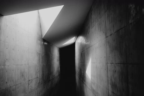 A stark concrete passage with a beam of light across its walls