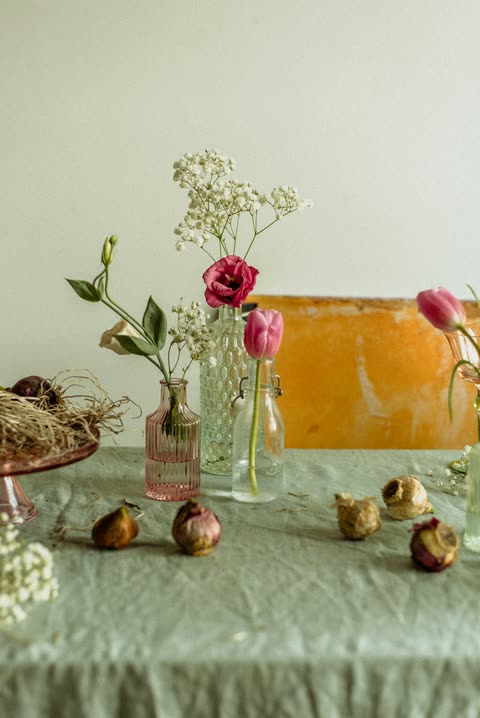 Small flowers in glass vases arranged with bulbs across a painted surface