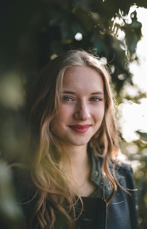 A woman in warm backlight outdoors, looking toward the camera
