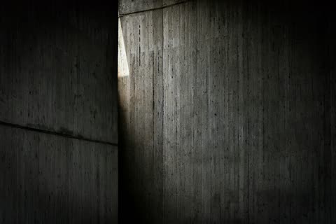 A narrow line of daylight falls between tall dark concrete walls